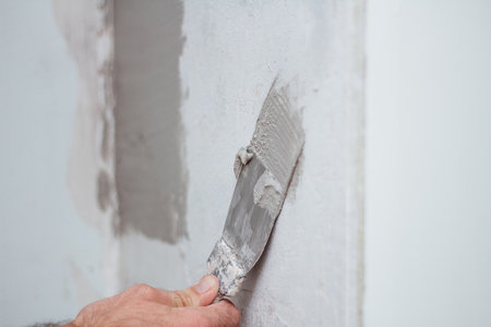 man hand with trowel plastering a wall, skim coating plaster walls.の写真素材