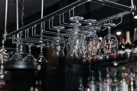 Empty and clean wine glasses hang upside down over the bar.の写真素材