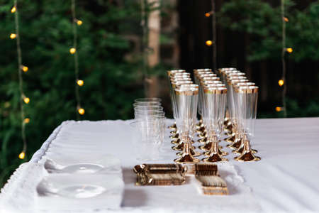 Three rows of glasses for champagne or wine and cutlery stand on table.の写真素材