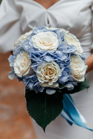 delicate wedding bouquet in the hands of the bride in the rustic style. Sunny clear day, white dress and rosesの写真素材
