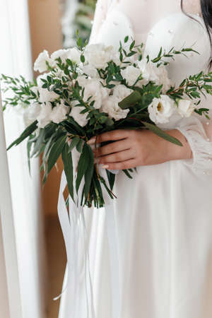 delicate wedding bouquet in the hands of the bride in the rustic style. Sunny clear day, white dress and rosesの写真素材
