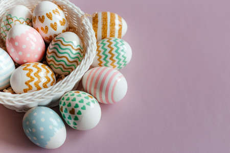Easter eggs in pastel colors with a pattern in white basket on pink background.の写真素材