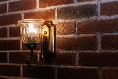 Retro-style lamp hangs on a red brick wall, copy space.の写真素材