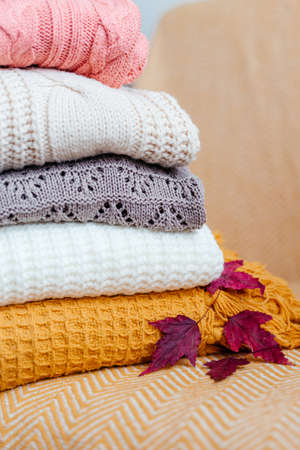 Stack of soft warm plaids and an autumn leaves close-up.