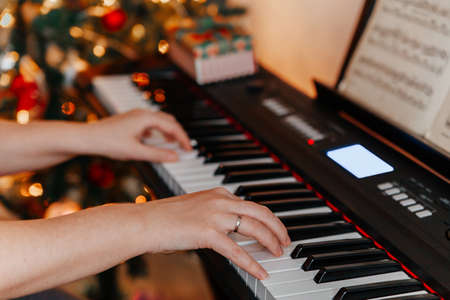 close up of many hands plays on Piano Keys with Christmas treeの写真素材