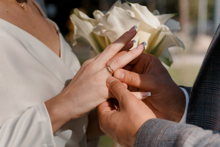 Groom putting golden ring on bride's finger during wedding ceremony. Hands with rings close upの写真素材