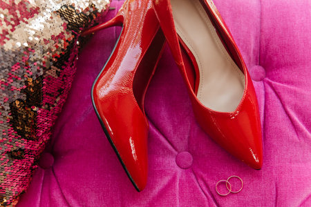 Red patent leather shoes of the bride near gold wedding ringsの写真素材