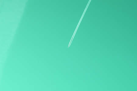white line from an airplane on the sky. mint green colorの写真素材