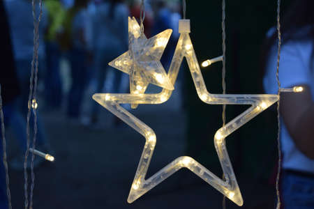 A garland in the form of a star glows in the dark on a dark blue