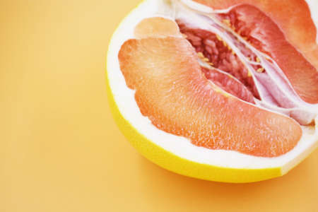 half red pomelo with a yellow peel on a colored background