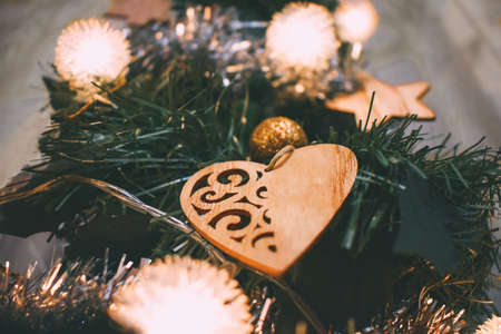 A wooden toy in the form of a heart hangs on a Christmas tree, closeup. Christmas toys and garland lightsの写真素材