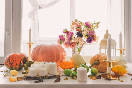 Various pumpkins, candles and a bouquet in a vase on the windowsill. Autumn decorations.の写真素材