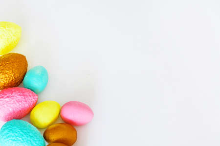 Pink, yellow, blue and gold Easter eggs on a white background. Copy space.の写真素材