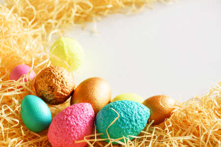 Eggs of different colors on wood chips. Easter background.の写真素材