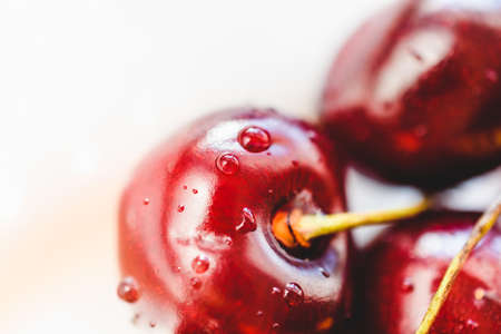 Ripe sweet cherries with drops of water on a white background close-up.