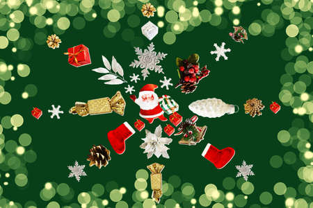 Snowflake made from Christmas decorations on a green background with bokeh. Christmas background. Santa Claus, Christmas sock, snowflakes, gifts, pine cones and candies.の写真素材