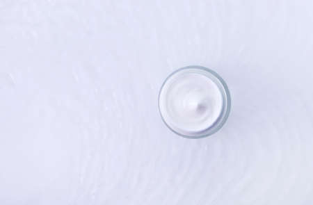 jar of cream in water with wave texture on light background
