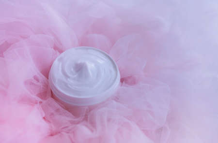 Jar of cream on a background of pink fabric