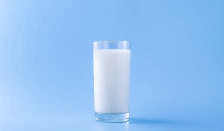 milk in a glass on a blue background with space for textの写真素材