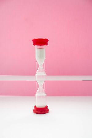 hourglass on pink background with white sand inside