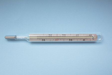 Mercury thermometer shows subfebrile temperature on a blue background.