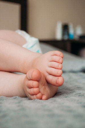 Childrens bare feet on the bed, on the gray blanket. Photo of Cute feet of a sleeping baby.の写真素材