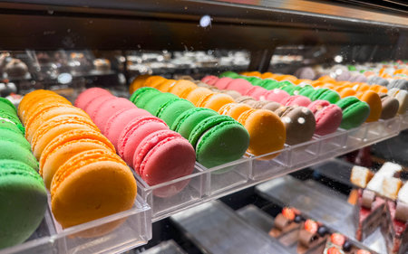 Photo of a glass bakery counter with desserts, colorful sweet macaroons.の写真素材