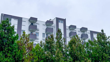 Photo of Modern Apartment Building with Greenery. Contemporary Architecture Surrounded by Lush Trees.の写真素材