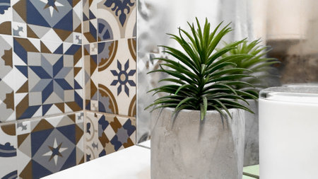 Minimalist Bathroom Decor with Concrete Planter and Patterned Ceramic Tiles. A stylish and modern setup featuring a green plant in a concrete pot alongside intricate geometric tile patterns.の写真素材