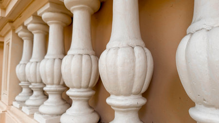 Close-up photo of elegant white balusters in a row, showcasing their classic architectural design and texture. Architectural projects, interior design concepts, decorative details.の写真素材