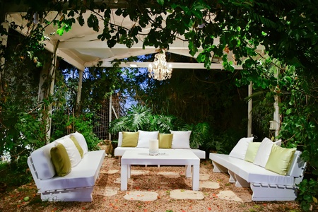 patio romantic in the evening with benches and pillows chandelier and table 