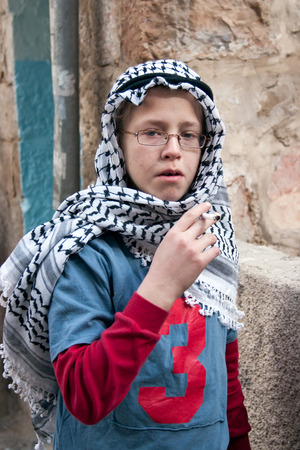 JERUSALEM, ISRAEL - MARCH 15, 2006: Purim carnival in the famous ultra-orthodox quarter of Jerusalem - Mea Shearim. Portrait of a boy children dressed in carnival costumes arab. In his hand a cigarette. Purim is celebrated annually according to the Hebrewのeditorial素材