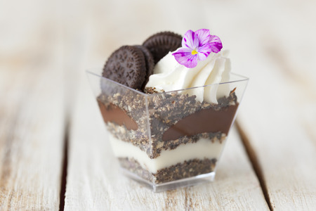 Trifle black and white chocolate with cookie. Decorated with a flower on old wooden white background. English traditional sweet dessert .の写真素材