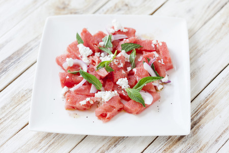 Fresh watermelon salad with feta cheese and mint on a white plateの写真素材