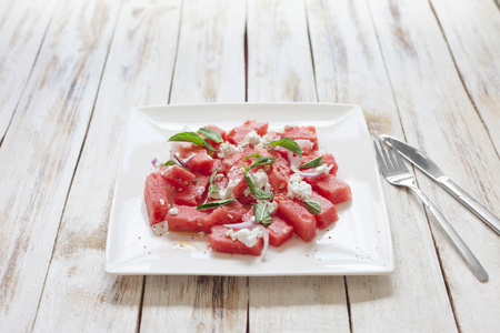 Fresh watermelon salad with feta cheese and mint on a white plateの写真素材