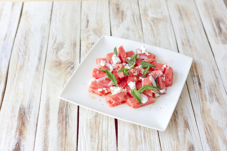 Fresh watermelon salad with feta cheese and mint on a white plateの写真素材