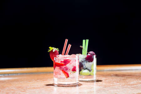 Two glasses of strawberry and grape mojitoes on marble table