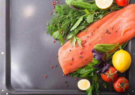 Raw salmon on a pan with salad, tomato and lemonの写真素材