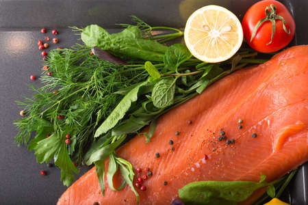 Raw salmon on a pan with salad, tomato and lemonの写真素材