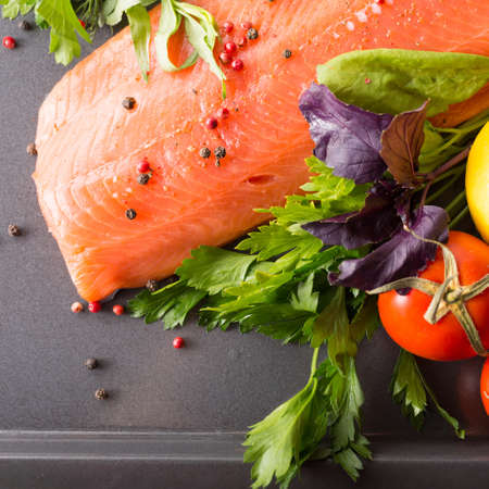 Raw salmon on a pan with salad, tomato and lemonの写真素材