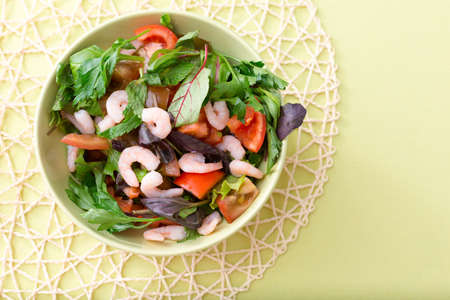 A bowl of green salad with tomatoes and shrimpsの写真素材