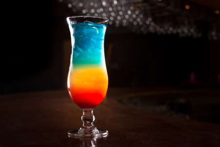 Rainbow cocktail on the bar stand with dark background. Shallow DOFの写真素材