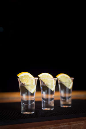 Three tequila shots with lemon on a bar ribber mat. Shallow DOF and tonedの写真素材
