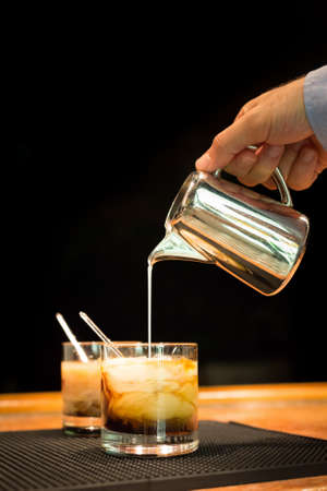 Preparation of white russian cocktails on the bar counter on rubber mat. Shallow DOF and marsala...