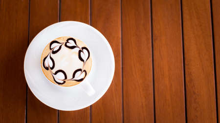A cup of cappuccino on a wooden table with heart shape chocolate decoration. Shallow DOF and lightly tonedの写真素材