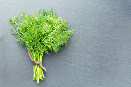 A bunch of fresh dill on a dark stone backgroundの写真素材
