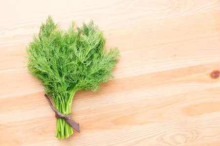A bunch of fresh dill on a light wooden background. Horizontal photoの写真素材