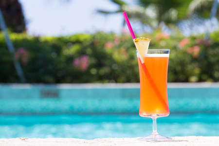 Glass of Mai Tai cocktail on the pool nosing at the tropical resort. Horizontal, cocktail on right...