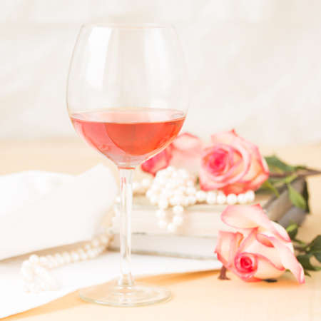 Glass of rose with vintage books and pearls. Lightweight background. Vintage style. Squareの写真素材