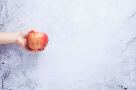 Go vegan! Concept of veganism. Vegan diet. Human hand with apple. Grey background. Horizontalの写真素材